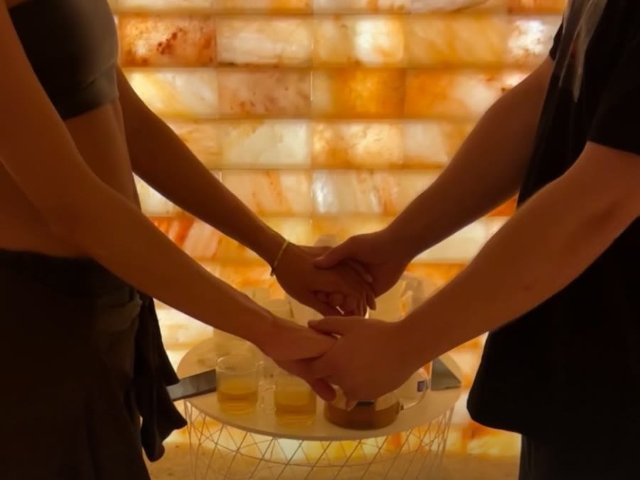 Dłonie trzymające się nad stolikiem z ziołową herbatą w grocie solnej